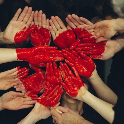 Foto: Zahlreiche Hände bilden eine Fläche mit roten Herz